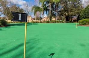 Ein Golfgrün mit einer Fahne mit der Aufschrift '1' und einem Pfeil.