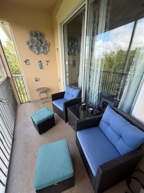 Ein Balkon mit Korbmöbeln, einem kleinen Tisch und dekorativer Wandgestaltung.