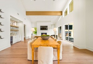 Ein geräumiger Essbereich mit Holztisch und -stühlen, einem Kamin und Blick ins Freie.