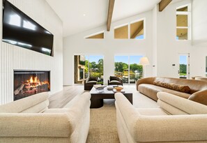 Ein geräumiges Wohnzimmer mit Kamin, Ledersofas und einem großen Fernseher.