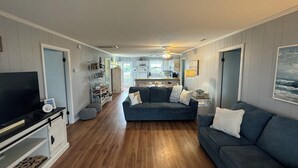 Een woonkamer met een televisie, een bank en een keuken op de achtergrond.