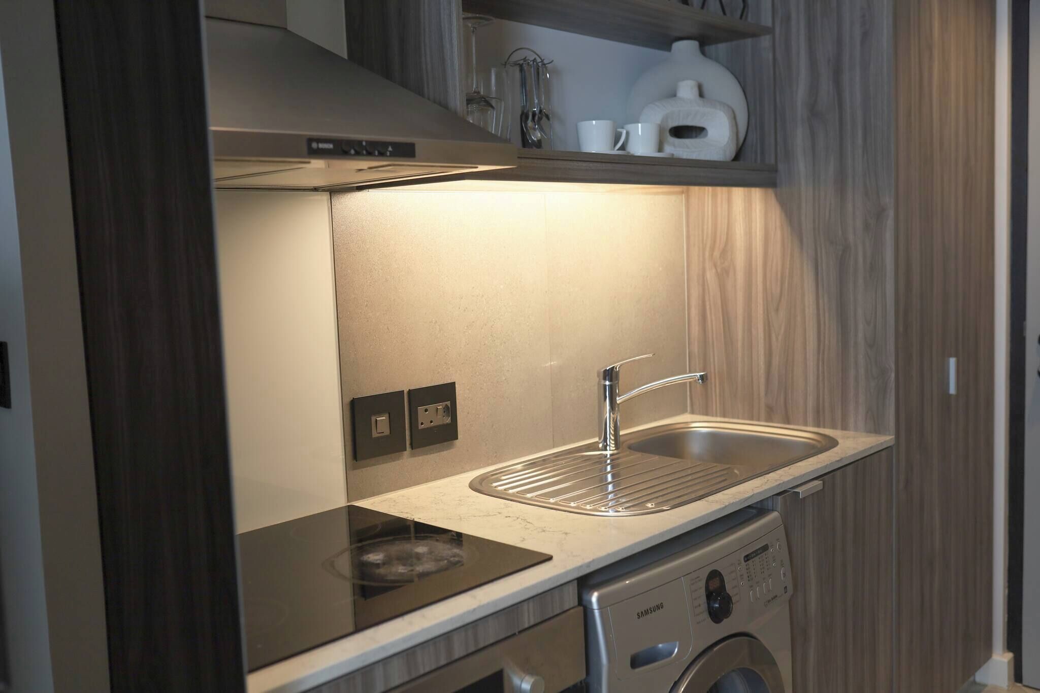 A compact kitchen with a built-in stove, a sink, and a washing machine.