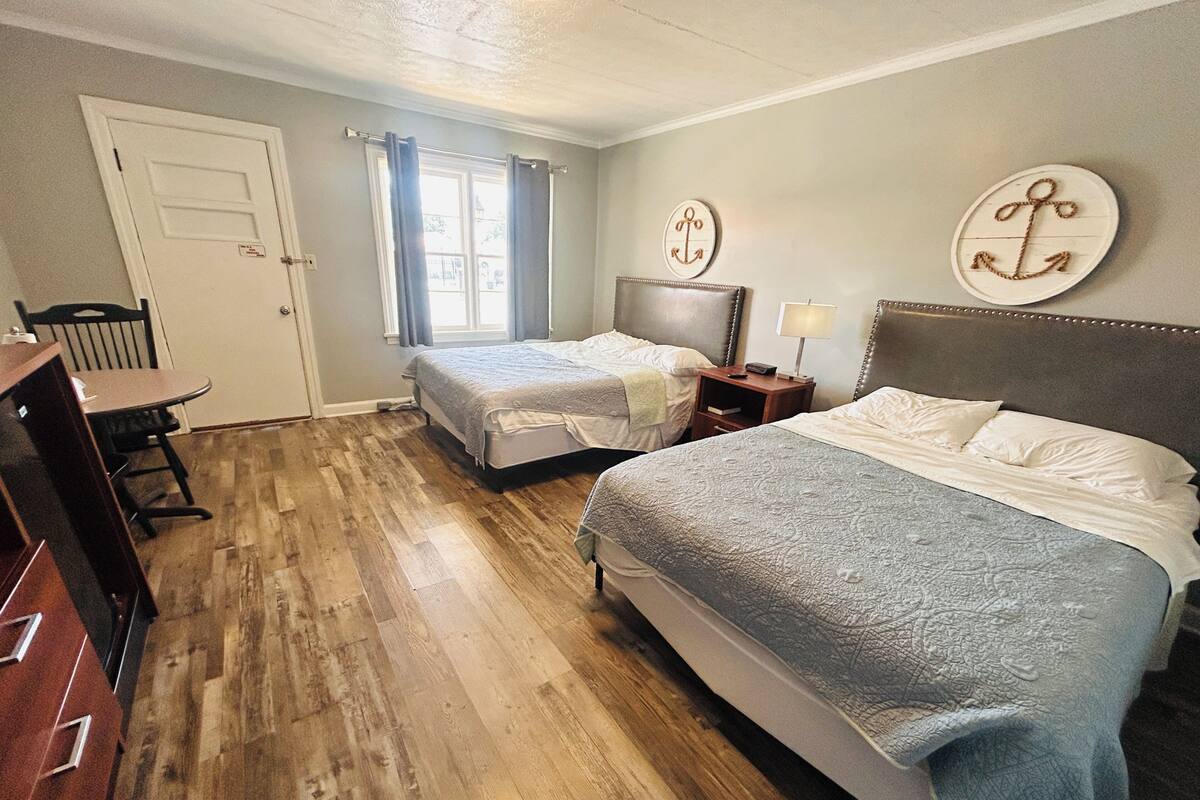 Une chambre d’hôtel avec deux lits, un bureau et une chaise.