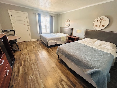 A hotel room with two beds, a desk, and a chair.