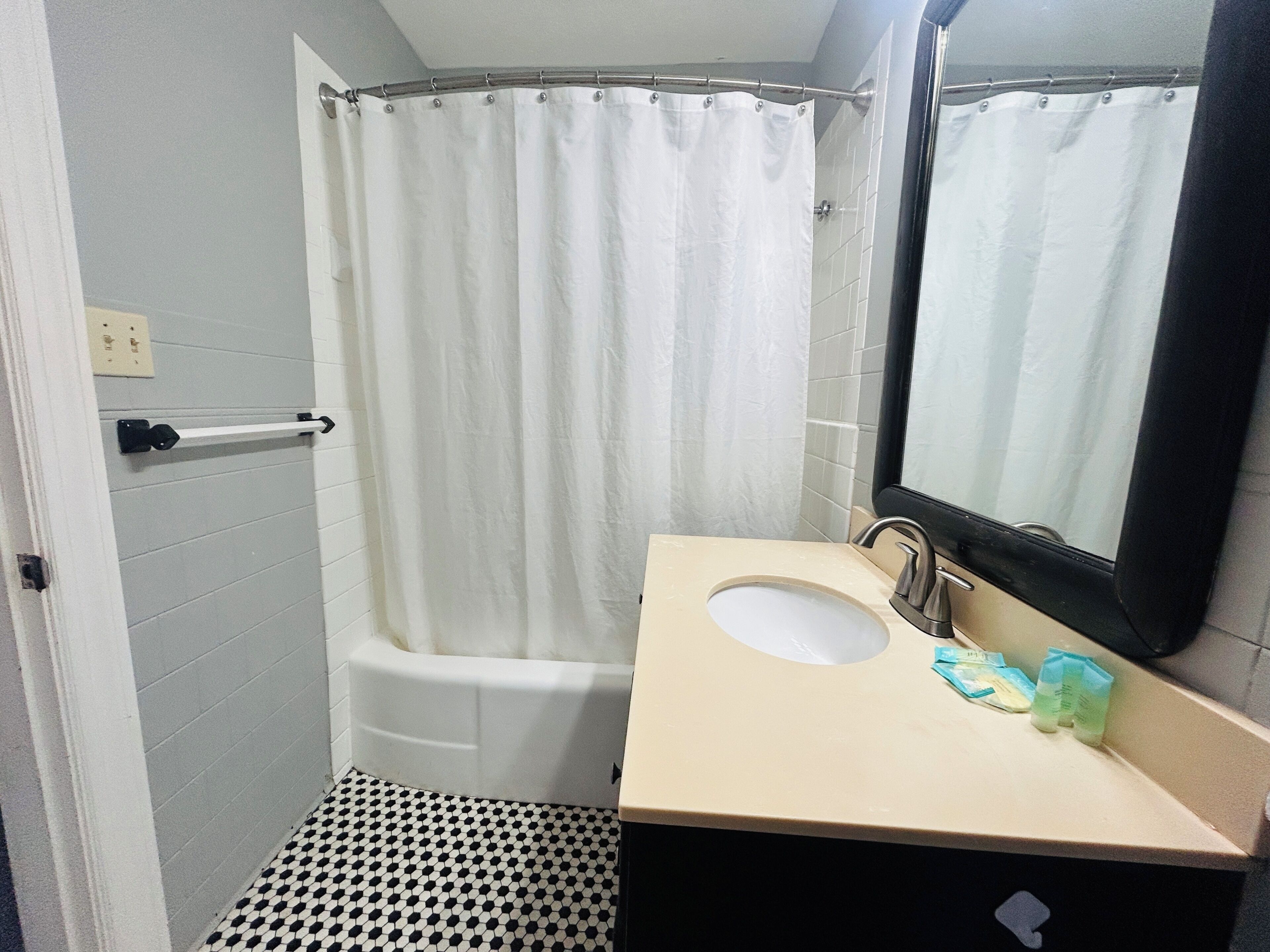 A bathroom with a bathtub, a sink, a mirror, and a shower curtain.