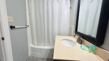 A bathroom with a bathtub, a sink, a mirror, and a shower curtain.
