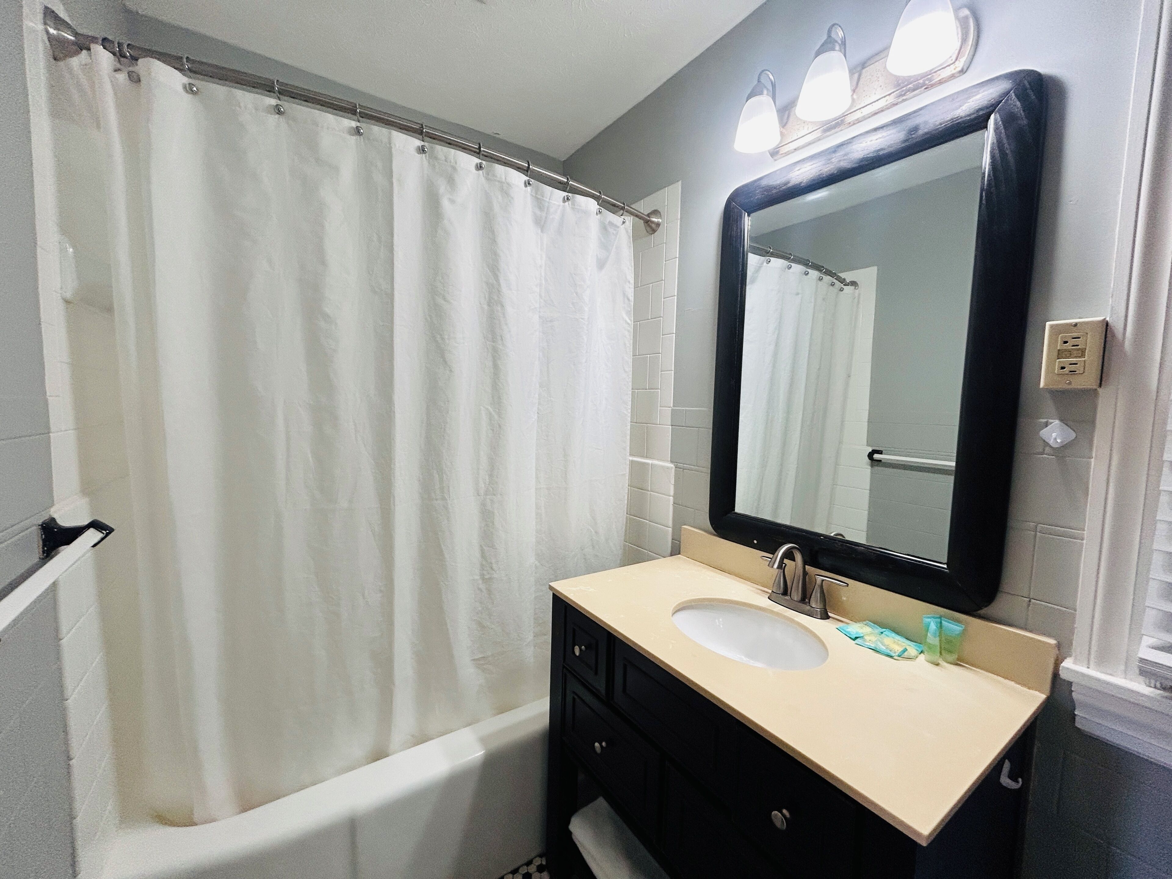 A bathroom with a bathtub, a sink, a mirror, and a shower curtain.