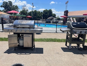 A poolside area with a barbecue grill and a gas station in the background. - 7 Gables Motel Burnside Near Somerset US 27 (Burnside)