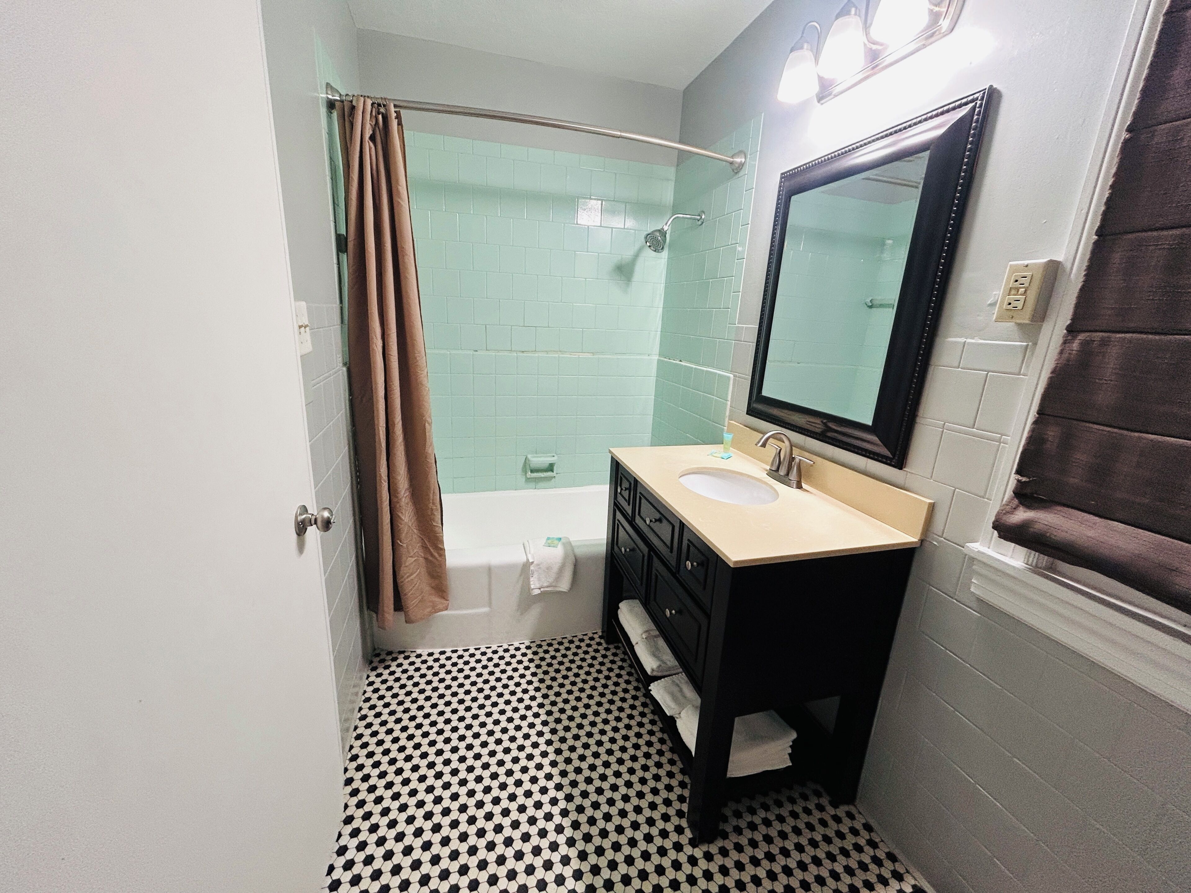 Une salle de bain équipée d’une baignoire, d’un lavabo, d’un miroir et d’un espace douche.