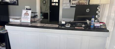 Un mostrador de recepción de hotel con una computadora, un teléfono y un cartel que indica que no se permite fumar.