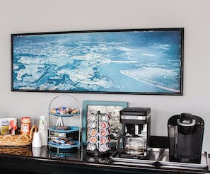 A kitchen counter with a coffee maker, a Keurig machine, a coffee pot, and a framed picture of a coastal landscape. - 7 Gables Motel Burnside Near Somerset US 27 (Burnside)