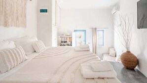 A modern bedroom with a large bed, a vanity, and a view of the kitchen. - Aura 1-bedroom apartment with AC and WiFi in charming Thira (Thira)