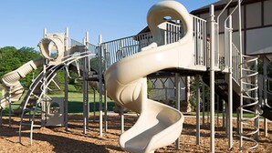 A playground with a spiral slide and climbing structures.