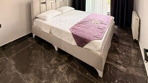 A bedroom with a bed, a ceiling light, a window with curtains, and a radiator. - BLACK HOUSE OTEL TURİZM  (Mersin)