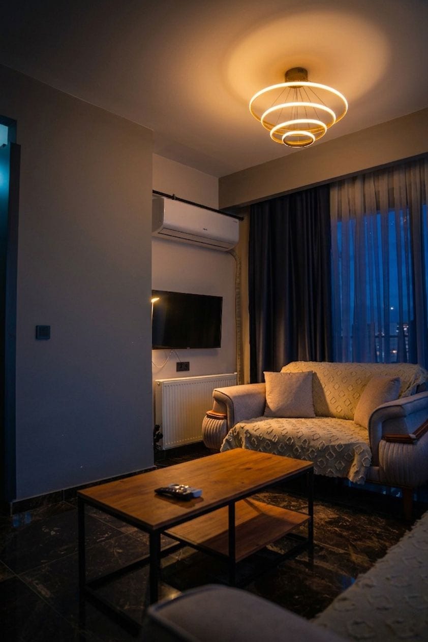 A modern living room with a sofa, a coffee table, and a TV mounted on the wall.