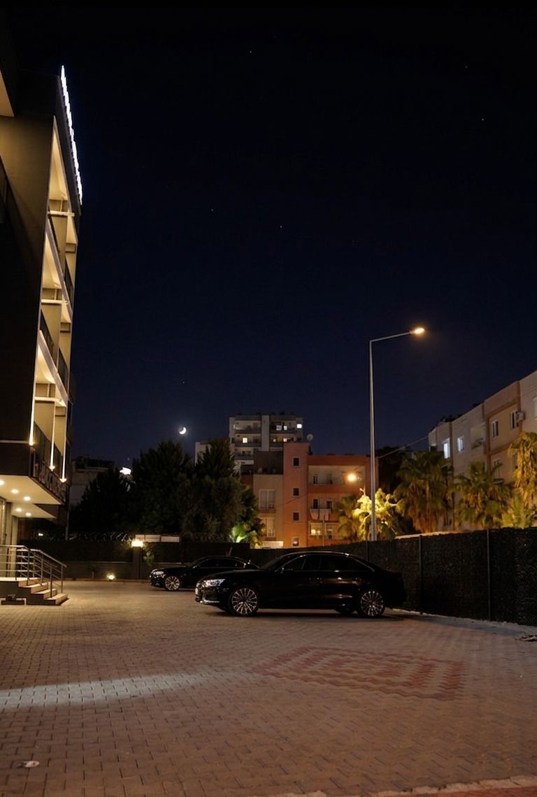 Ein Parkplatz bei Nacht, mit einem Gebäude links und einer Straßenlaterne rechts.