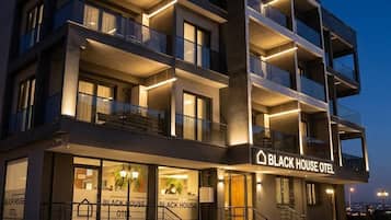 A multi-story building with balconies and a sign reading 'Black House Hotel.'