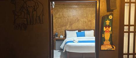 A bedroom with a bed, a nightstand, a wall painting, and a decorative piece.
