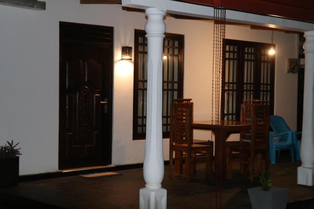 A room with a wooden table and chairs, a white pillar, and a door.