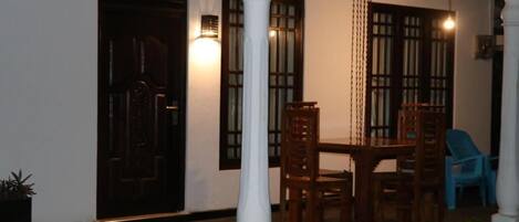 A room with a wooden table and chairs, a white pillar, and a door.