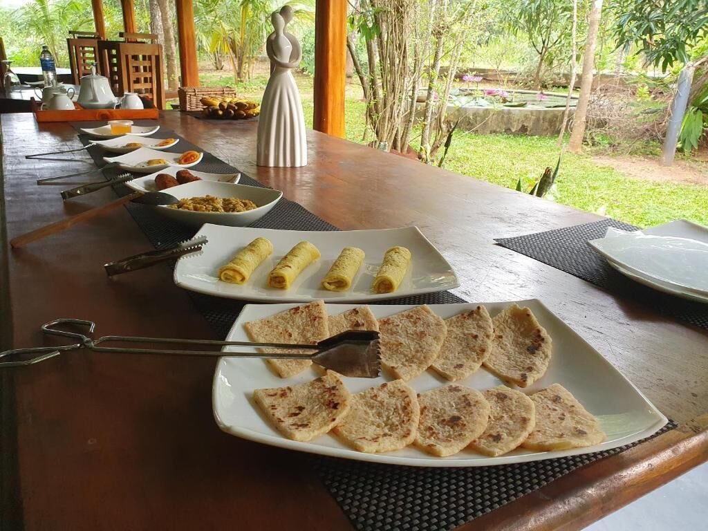 A breakfast buffet with various dishes and utensils on a wooden table.