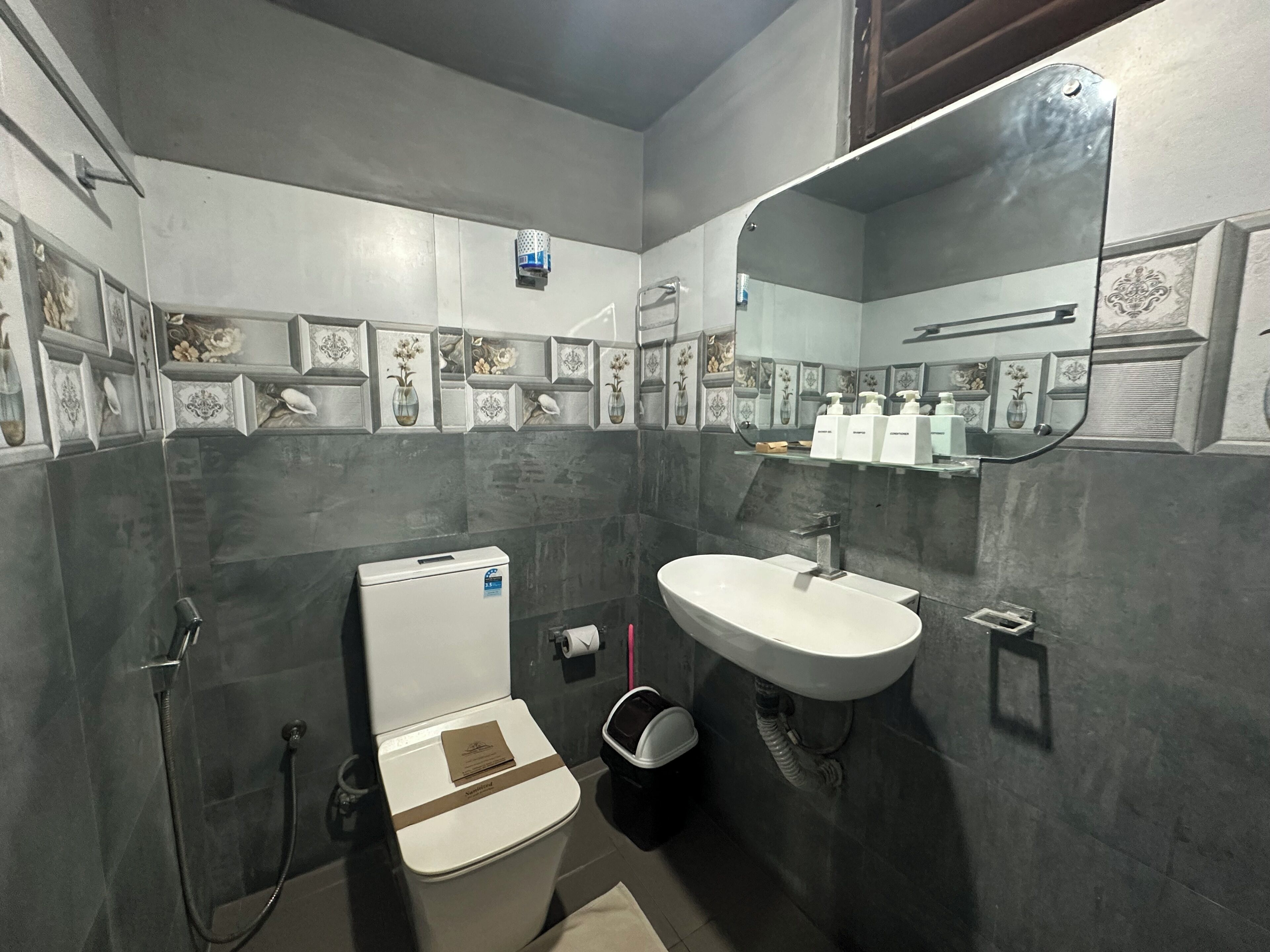 A bathroom with a toilet, sink, shower, and a mirror.