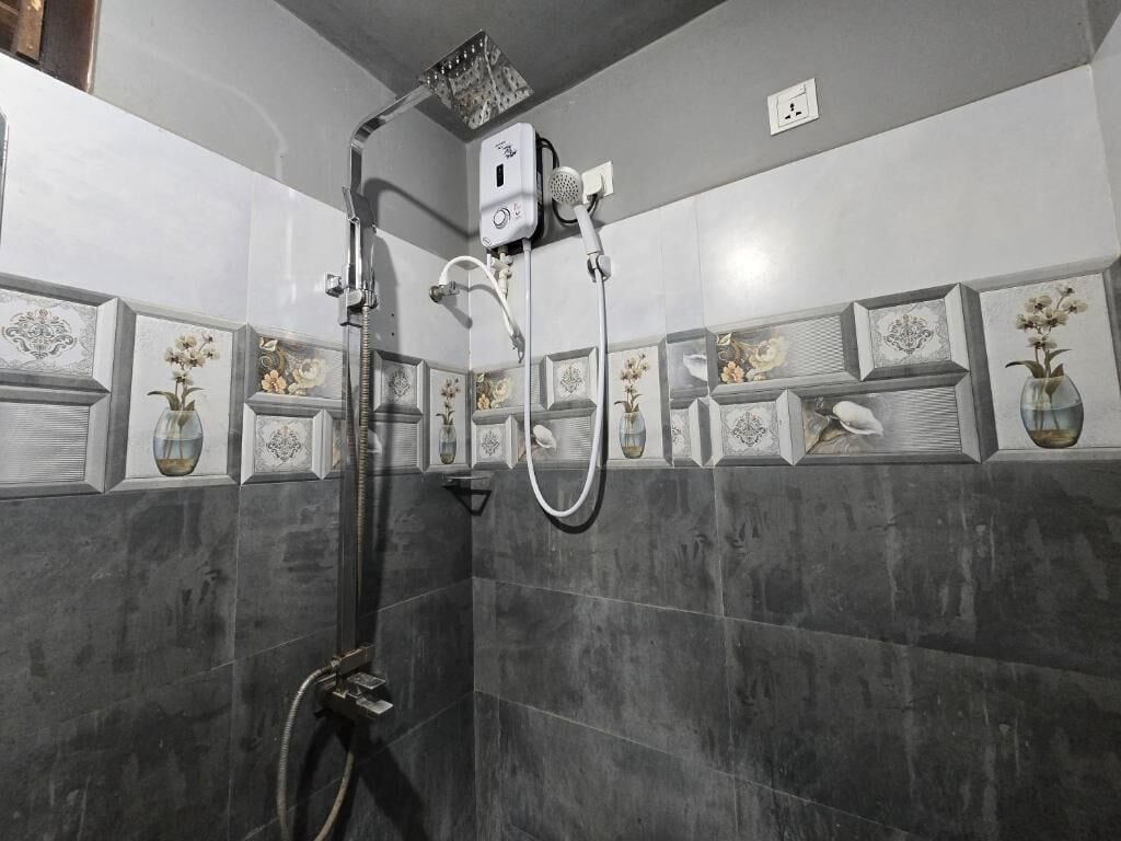 Un baño con ducha, paredes con azulejos y jarrones decorativos.