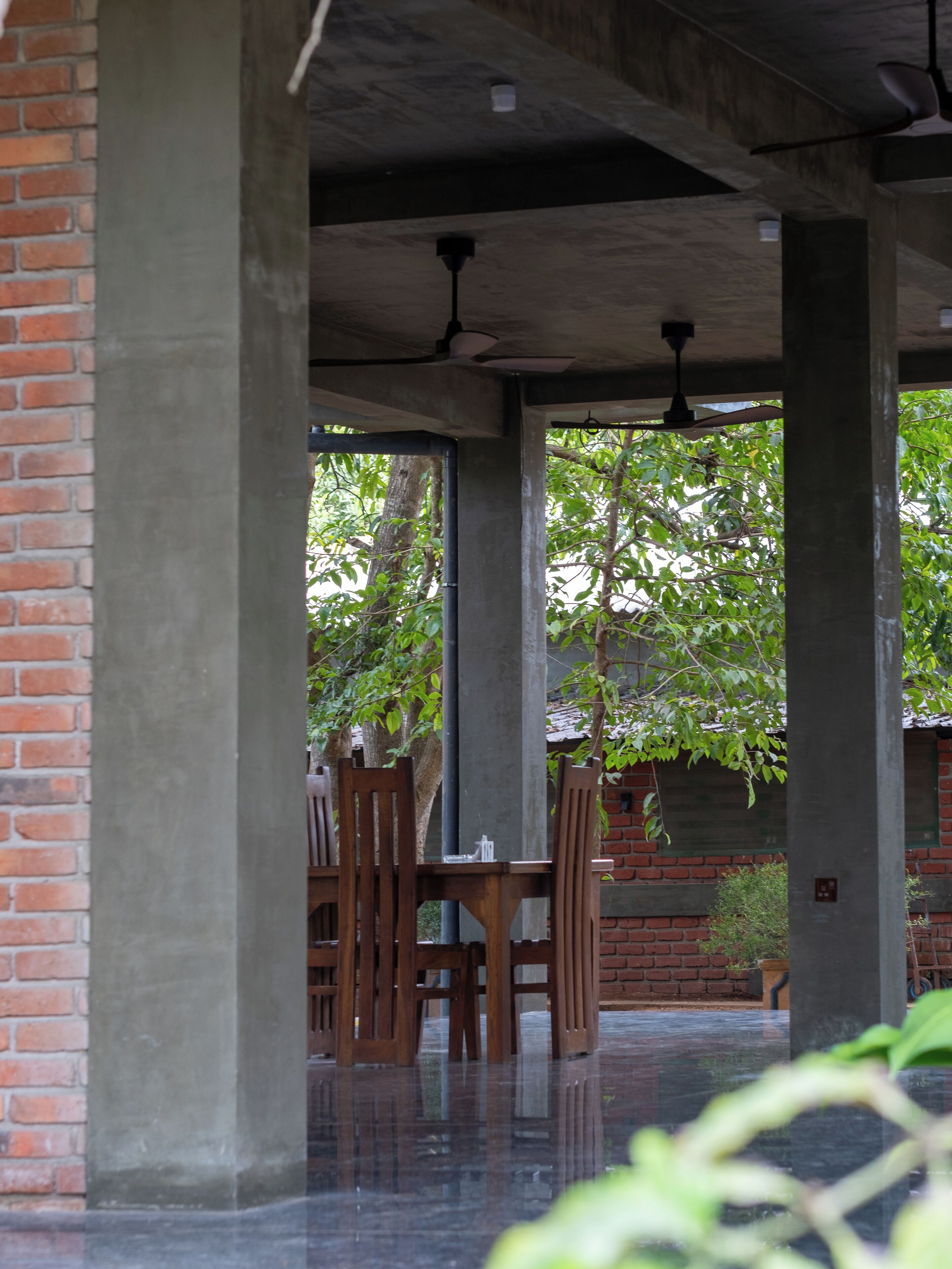 A covered outdoor seating area with brick walls, concrete pillars, and a glass enclosure.