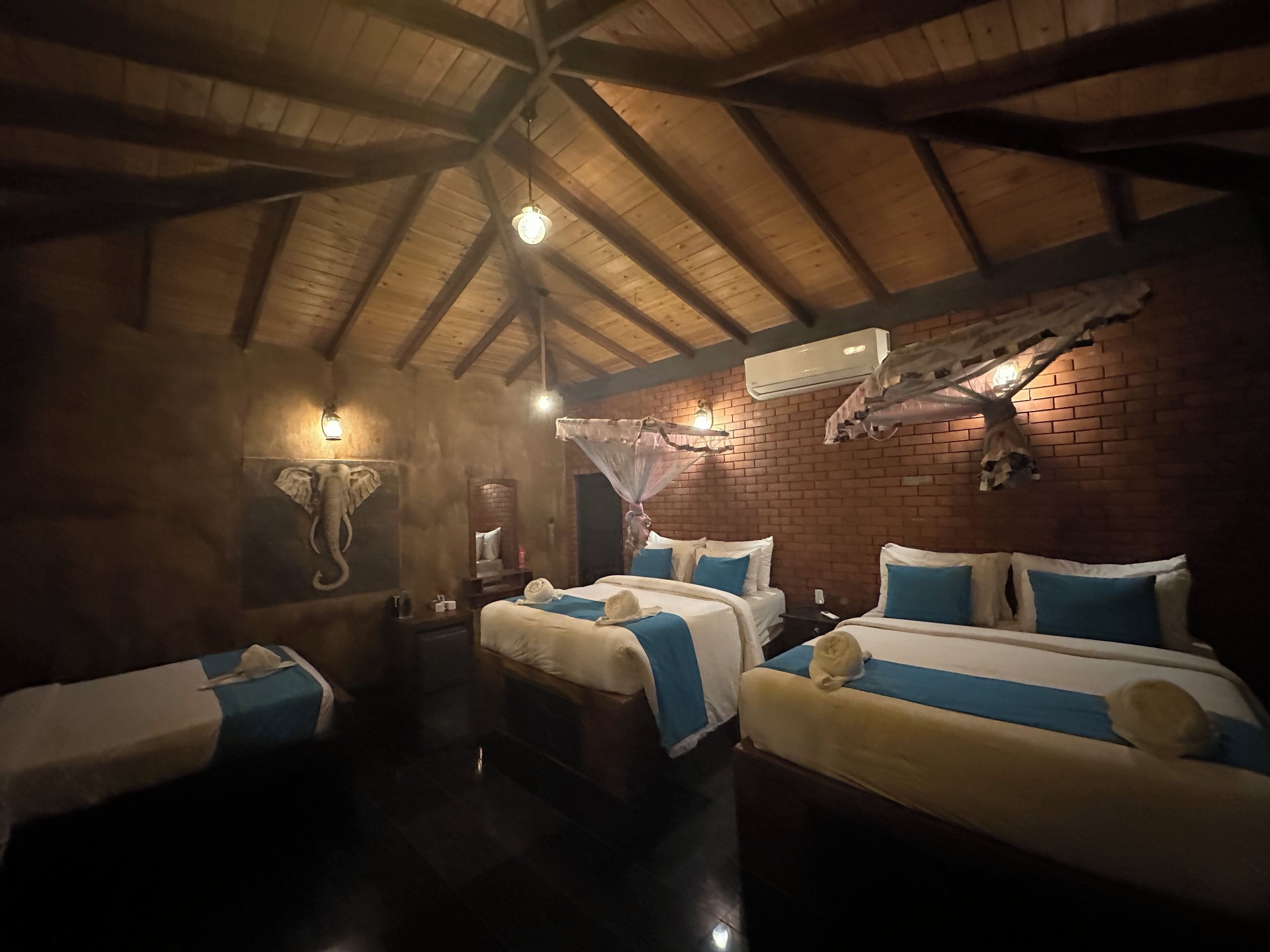 A room with a high wooden ceiling, brick walls, and a bed with a canopy.