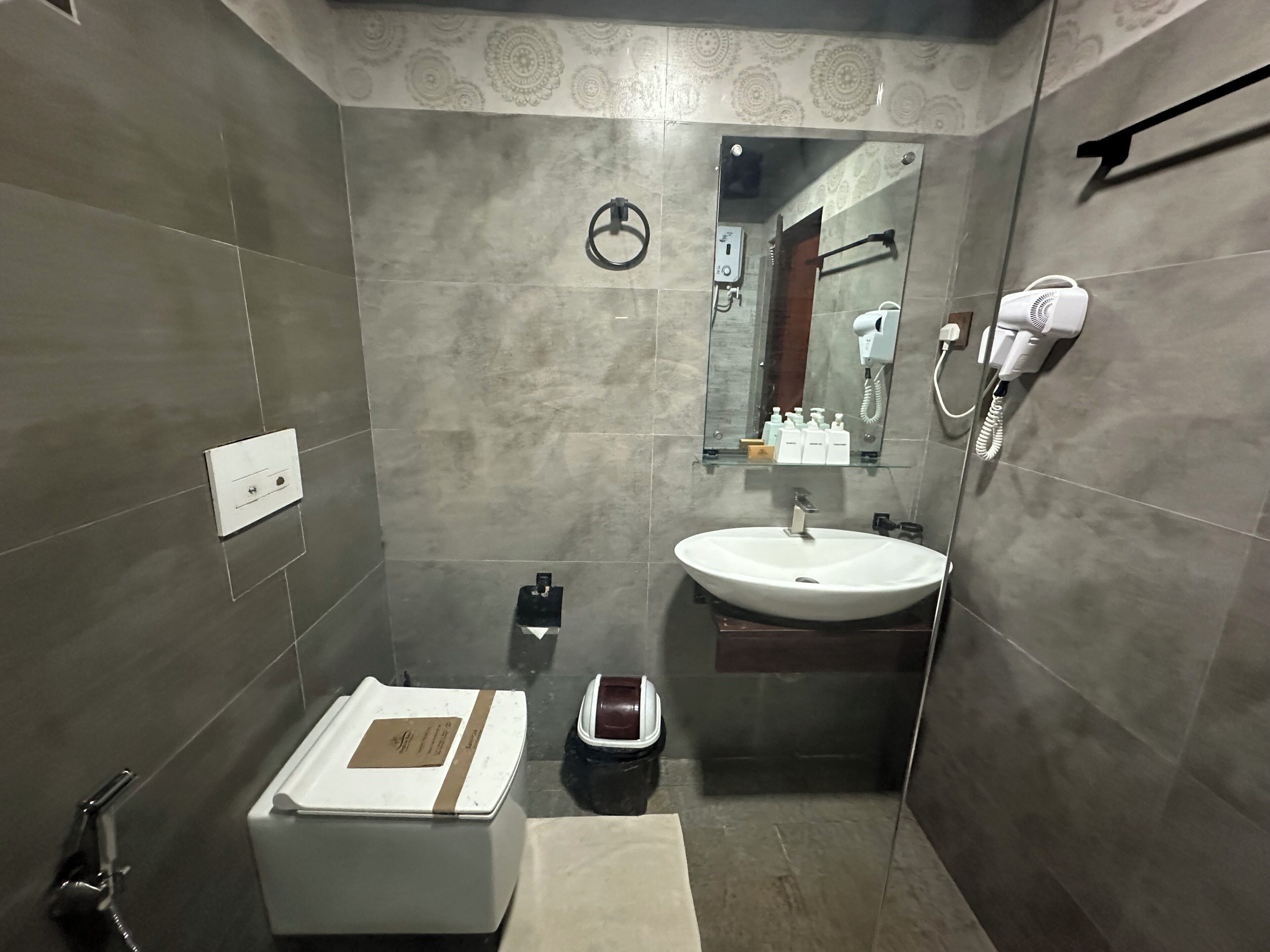 Un baño con lavamanos, espejo, toalla y una pequeña caja.