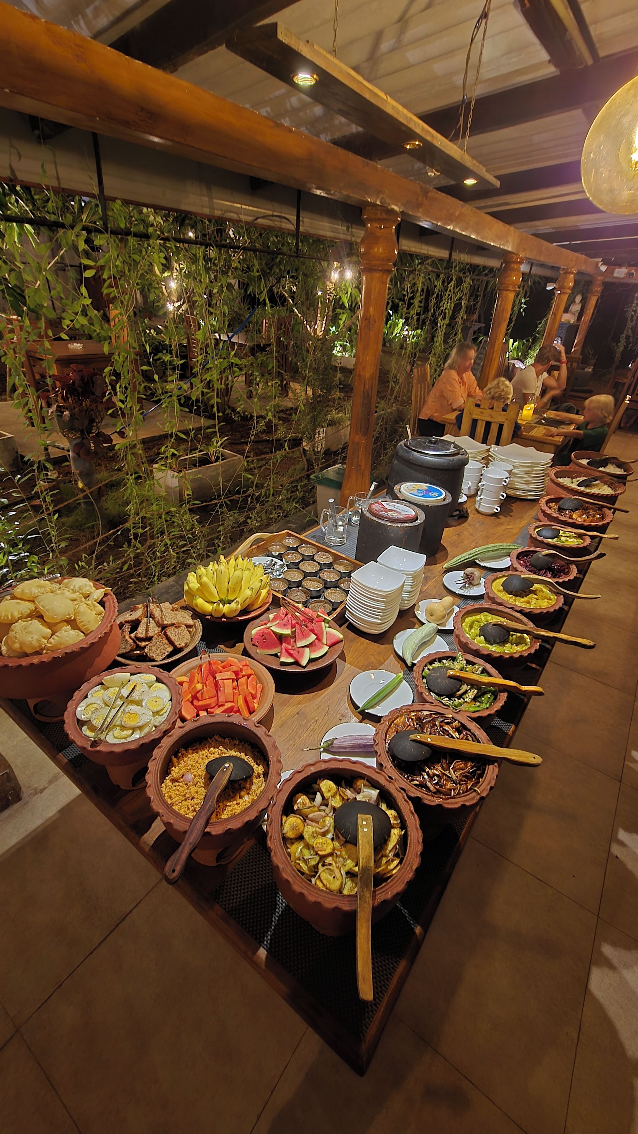 A buffet with various dishes and a long table.
