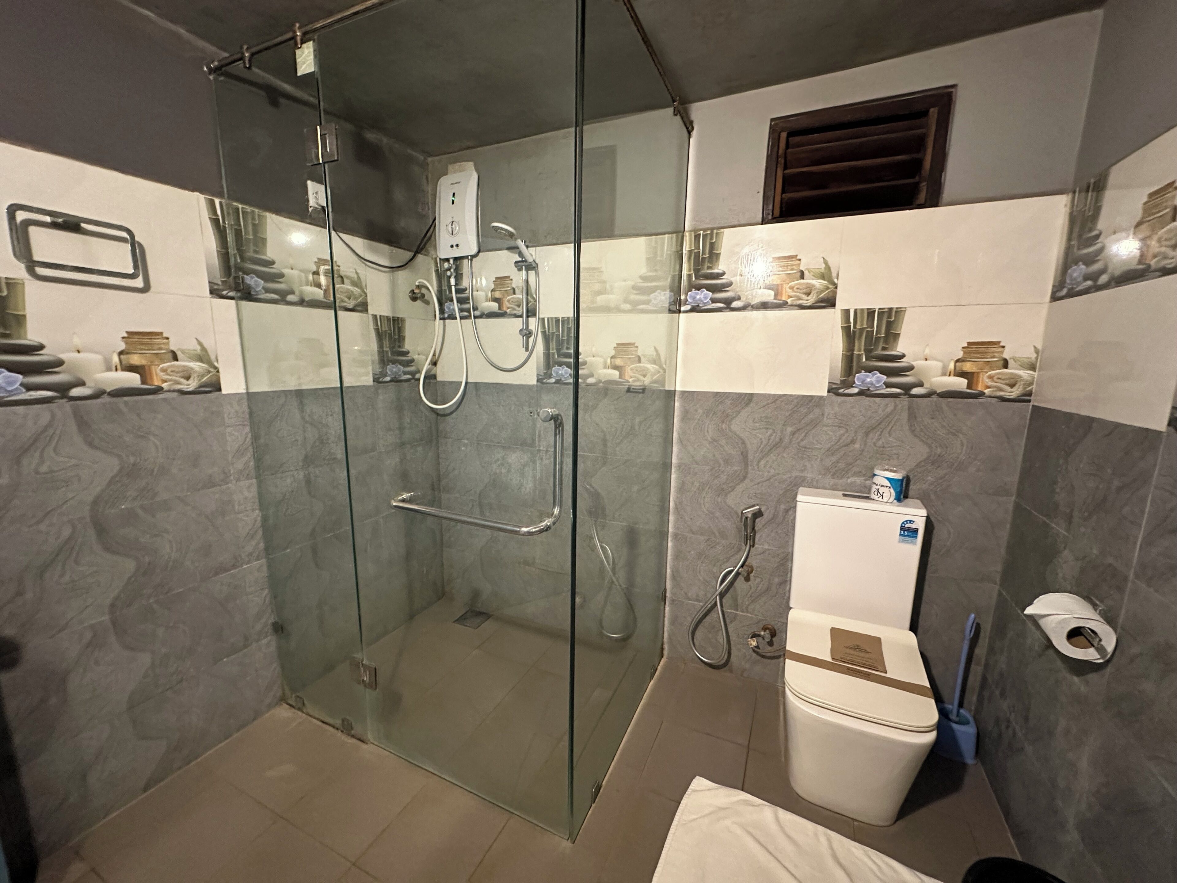 A modern bathroom with a glass-enclosed shower, a toilet, and a sink.