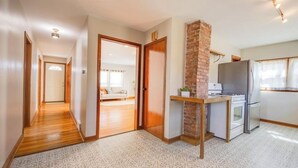 Ein Hotelzimmer mit einem gemusterten Boden, einer Küchenzeile mit Kühlschrank, Herd und Mikrowelle, einer Wand mit Ziegeln als Blickfang und einem Flur, der in ein weiteres Zimmer führt.