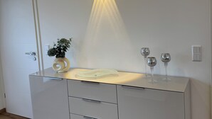 Ein modernes Badezimmer mit einem weißen Waschtisch, einem Glasbecken und einer Wandleuchte.