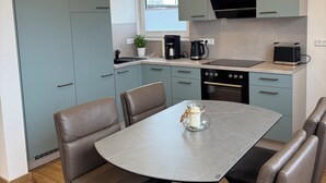 Eine moderne Küche mit Esstisch und Stühlen, eingebauten Geräten und einem Fenster.