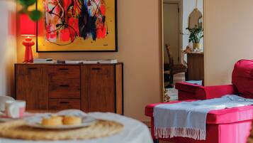 Una stanza con un armadio in legno, una sedia rossa, uno specchio grande e un quadro appeso al muro.