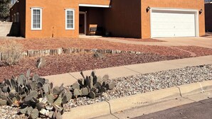 Uma casa térrea com garagem, um pátio e um jardim de cactos.