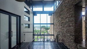 A modern interior with a balcony, large windows, and a stone wall. - Luxurious, Spacious 2-br (Johannesburg)