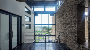 A modern interior with a balcony, large windows, and a stone wall. - Luxurious, Spacious 2-br (Johannesburg)