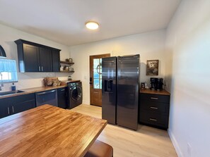 A modern kitchen with a wooden table, stainless steel appliances, and dark cabinetry.