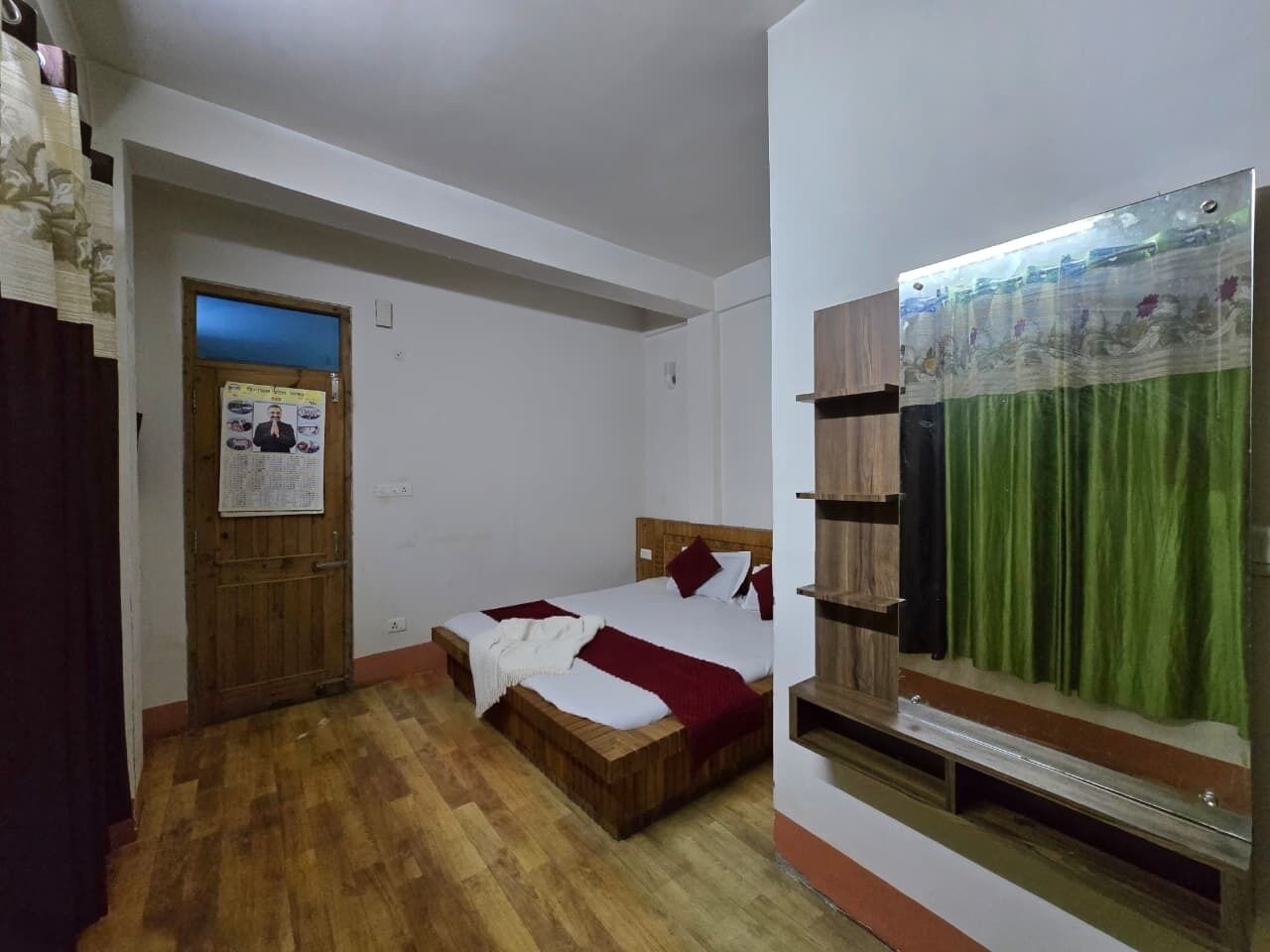 Un dormitorio con cama y puerta de madera, un espejo y una cortina verde.