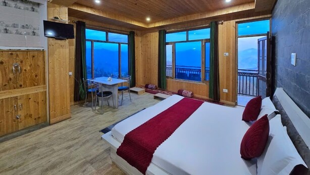 A bedroom with a large bed, a desk, and a view of the mountains. - Lucky Homestay (Theog)