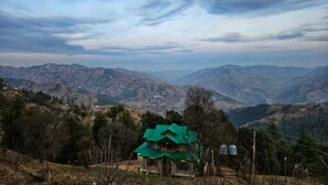 A mountainous landscape with a small house featuring a green roof. - Lucky Homestay (Theog)