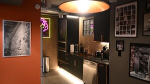 Eine moderne Küche mit Edelstahlgeräten, einem Holflanschrank und einem Neonlicht.