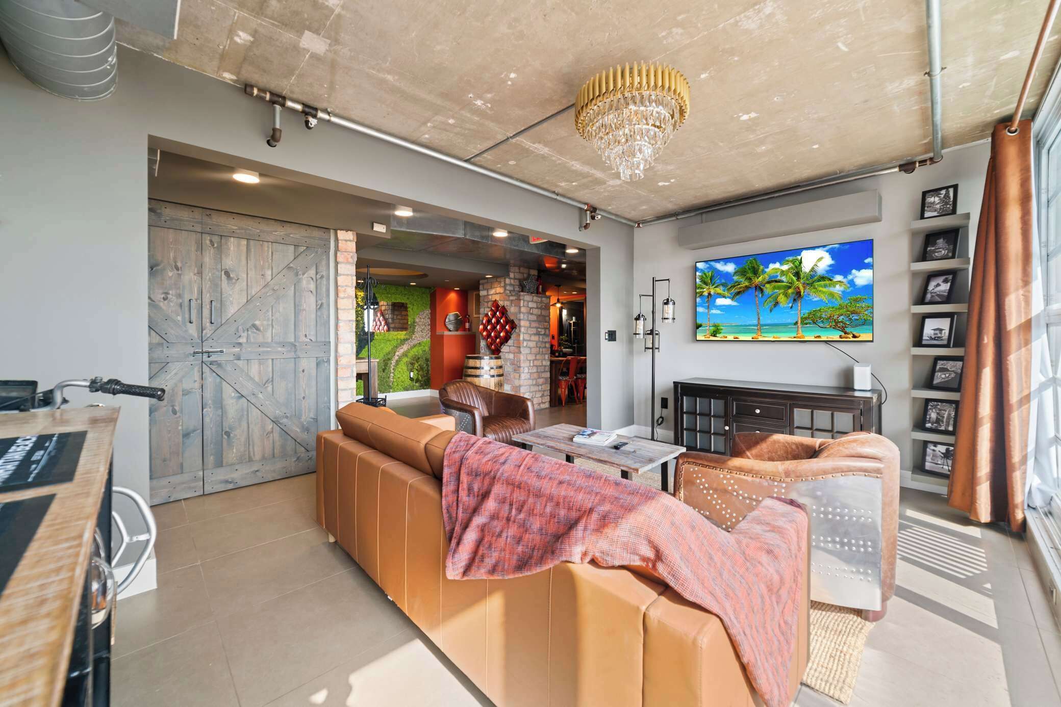 A modern living room with a large sofa, a television, and a chandelier.