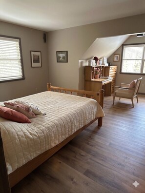 Un dormitorio con cama de madera, un escritorio, una silla y un aparador.