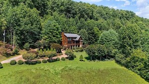 Una casa rodeada de un césped cuidado y un bosque frondoso.