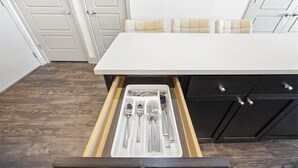 A kitchen with a white countertop, a drawer with utensils, and dark wooden flooring. - Modern Oasis + Pool, Gym + EV Charger (Frisco)