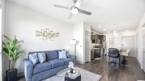 A modern living room with a sofa, coffee table, and a ceiling fan. - Modern Oasis + Pool, Gym + EV Charger (Frisco)