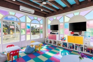 Ein Spielzimmer für Kinder mit farbigem Bodenbelag, einem Fernseher und einem Wasserspender.